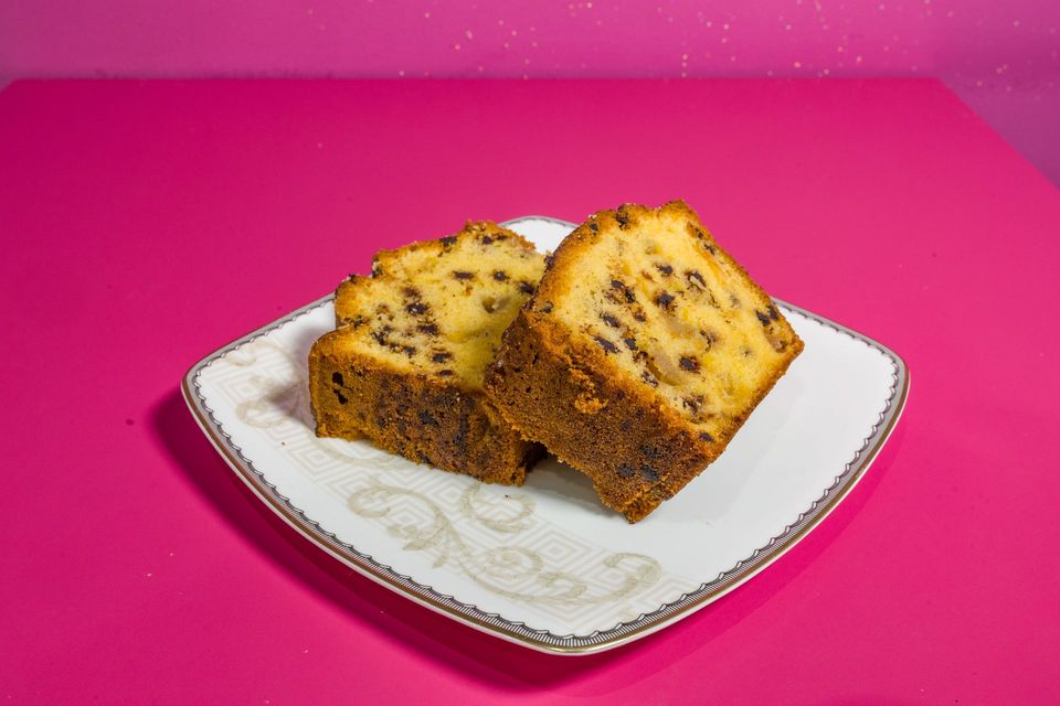 Due fette di panettone su un piatto bianco su uno sfondo rosa acceso