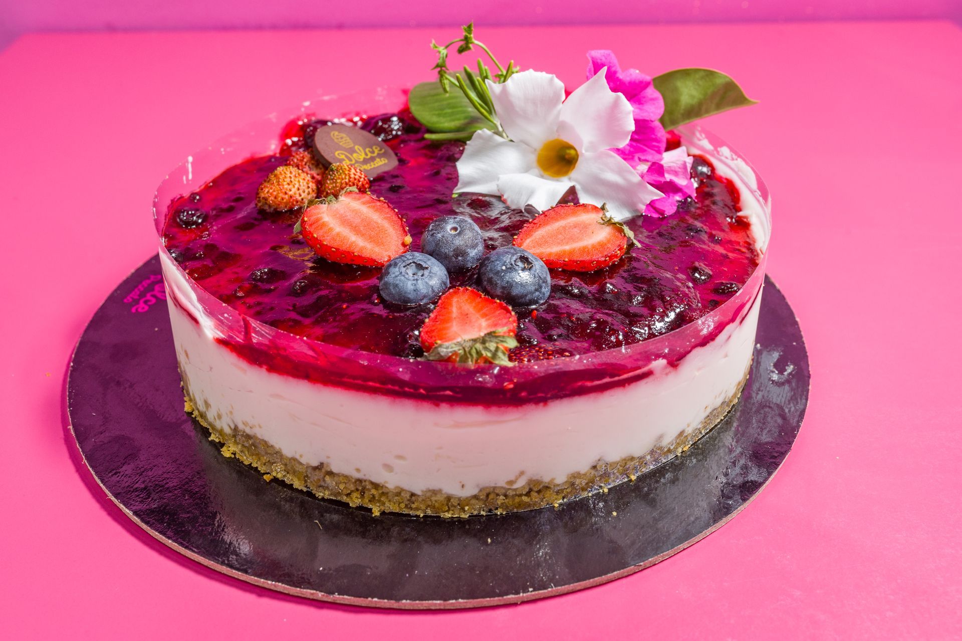 Cheesecake con frutti di bosco su un vassoio argentato su sfondo rosa