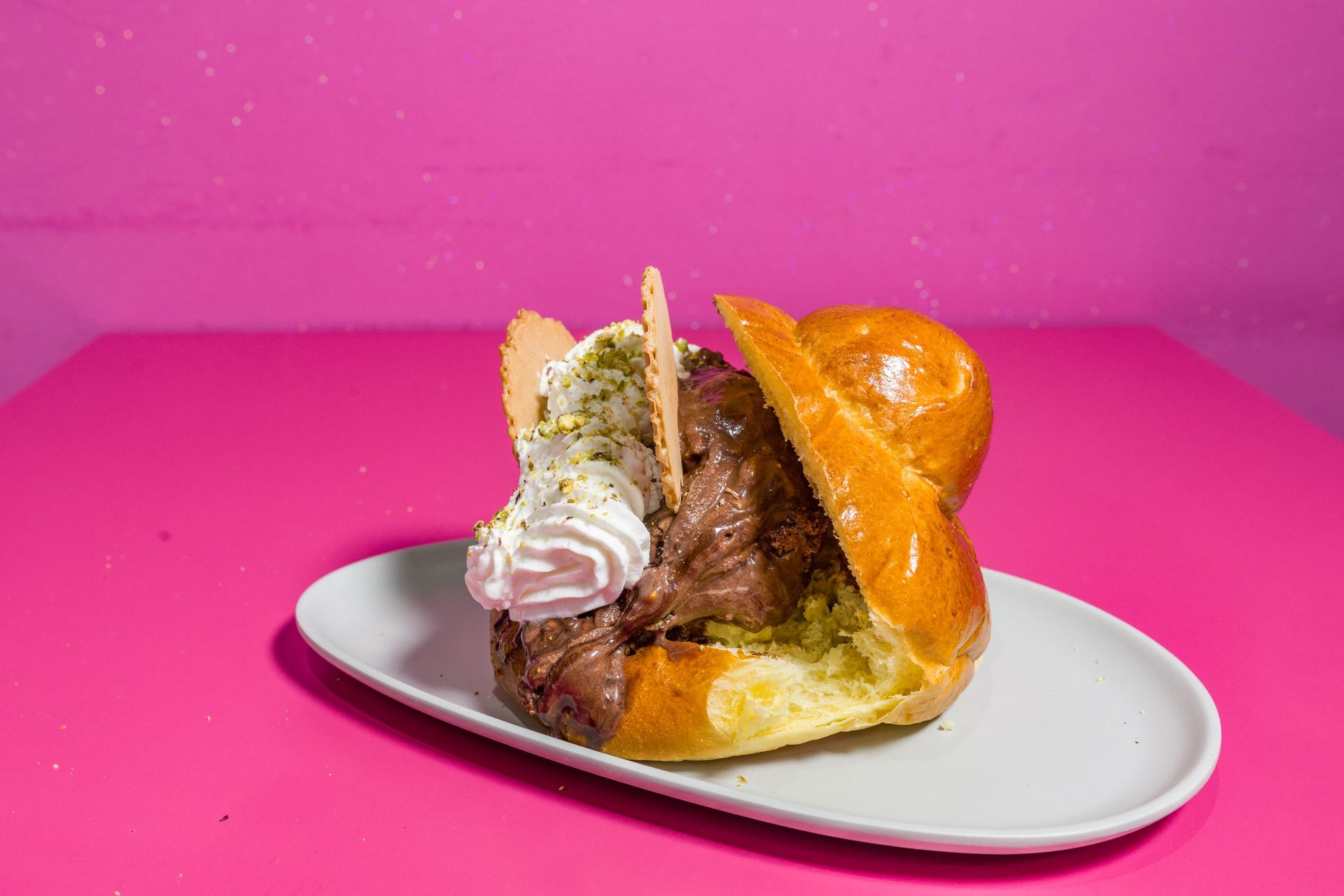 Panino con carne e cipolle su un piatto bianco su uno sfondo rosa acceso