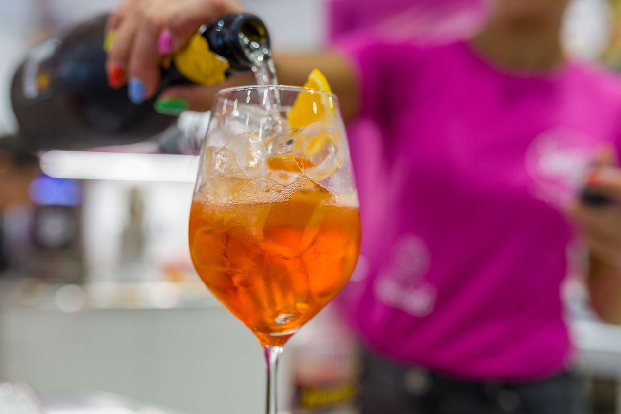 Un cocktail all'arancia viene versato con ghiaccio e guarnito con una fetta d'arancia in un bar.