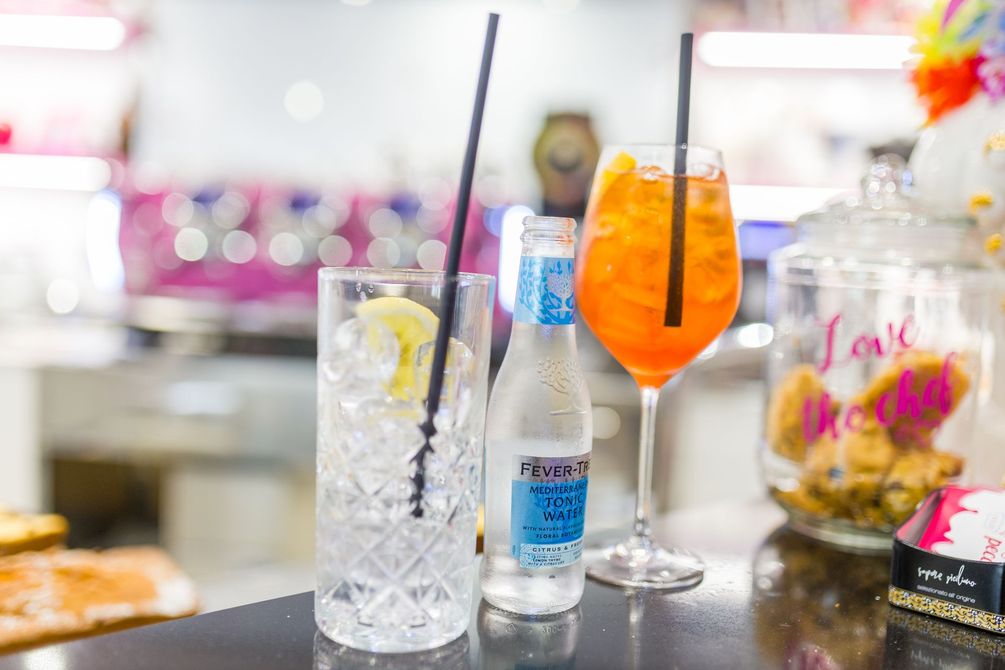 Cocktail bar con una bevanda ghiacciata, spritz all'arancia e una bottiglia su un bancone lucido.