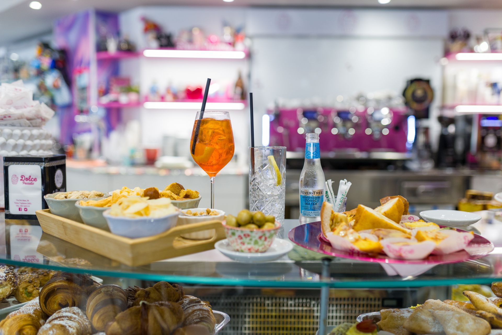 Buffet di dolci con pasticcini, frutta e una bevanda all'arancia su un bancone di vetro in una caffetteria