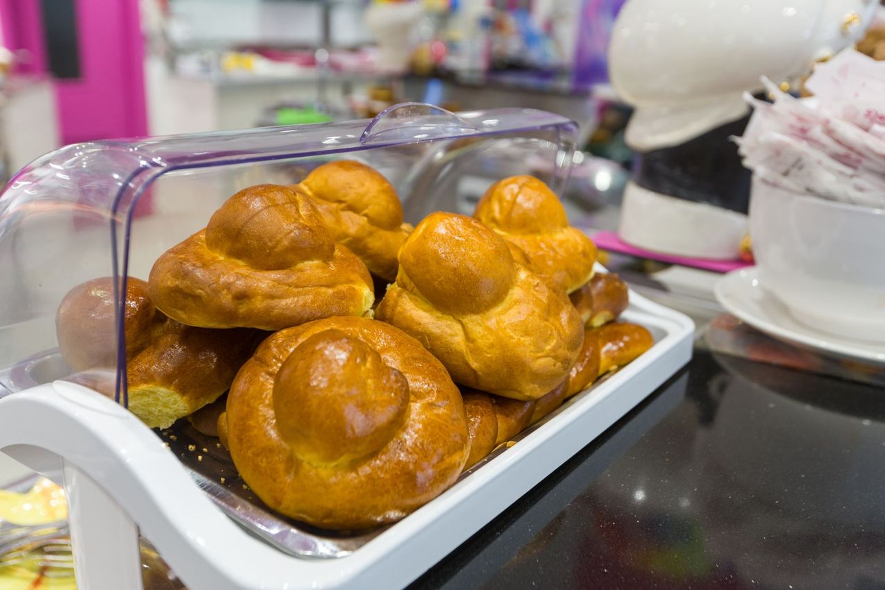 Un vassoio di pasticcini dorati su un bancone accanto a una ciotola da dessert.