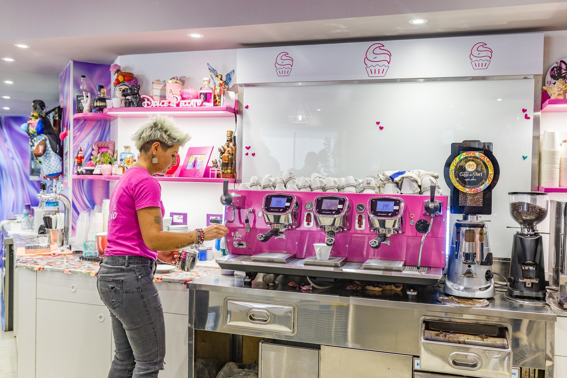 Barista che utilizza una macchina per espresso rosa in un caffè luminoso