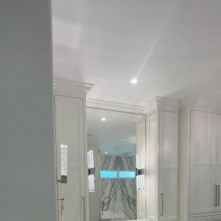 Bright white bathroom with mirrored cabinets, recessed lights, and a shower curtain in the center.
