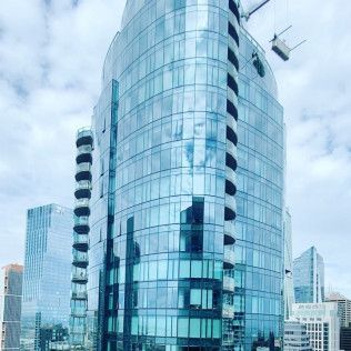 Glass office tower with curved facade against a cloudy city skyline