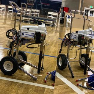 Two small wheeled robots on a gym floor with blue court lines and chairs in the background