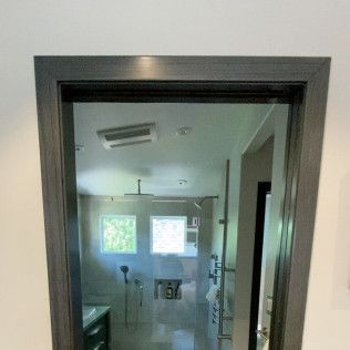 View through a doorway into a small modern bathroom with a window and wall-mounted fixtures.