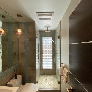 Modern bathroom with a sink, toilet, shower, and frosted glass window.