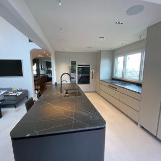 Modern kitchen with black island, sink, built-in cabinets, and large window views