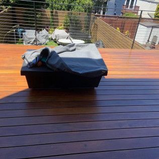 Covered outdoor grill on a wooden deck with a backyard fence and patio in the background