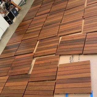 Stacks of reddish-brown wooden planks arranged on a warehouse floor.