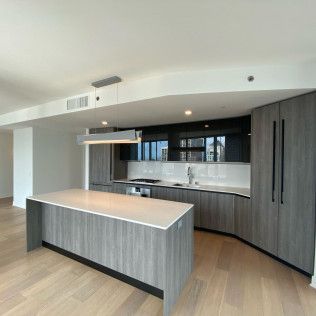 Modern kitchen with gray cabinets, curved island, white backsplash, and light wood floors