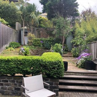 Terraced garden with stone steps, lush greenery, and a white patio chair in the foreground