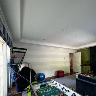 Finished basement playroom with foosball table, exercise balls, and striped walls
