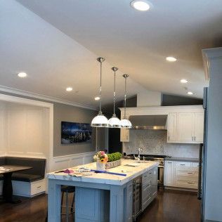 Modern kitchen with large island, white cabinets, stainless appliances, and pendant lights