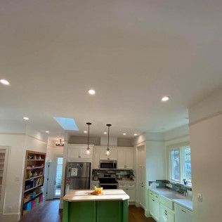 Bright white kitchen with island, stainless appliances, pendant lights, and large windows