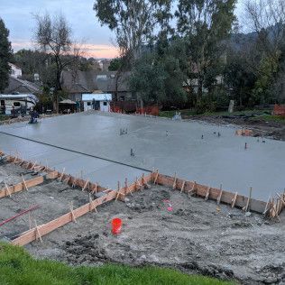 Fresh concrete foundation slab with wooden formwork at a construction site at dusk