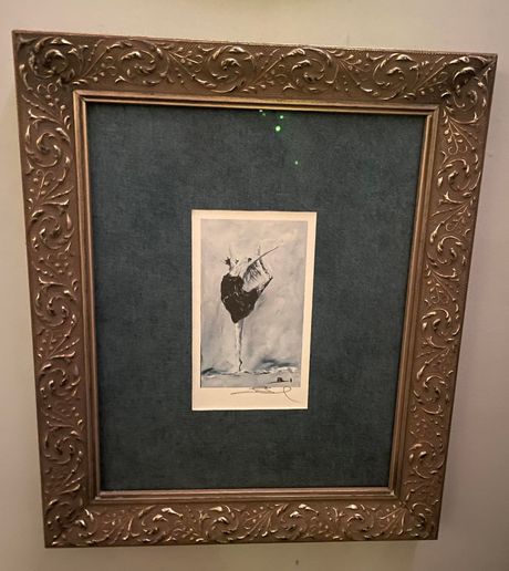 Framed print of a dancer performing an arabesque, featuring a dark mat and an ornate gold frame.
