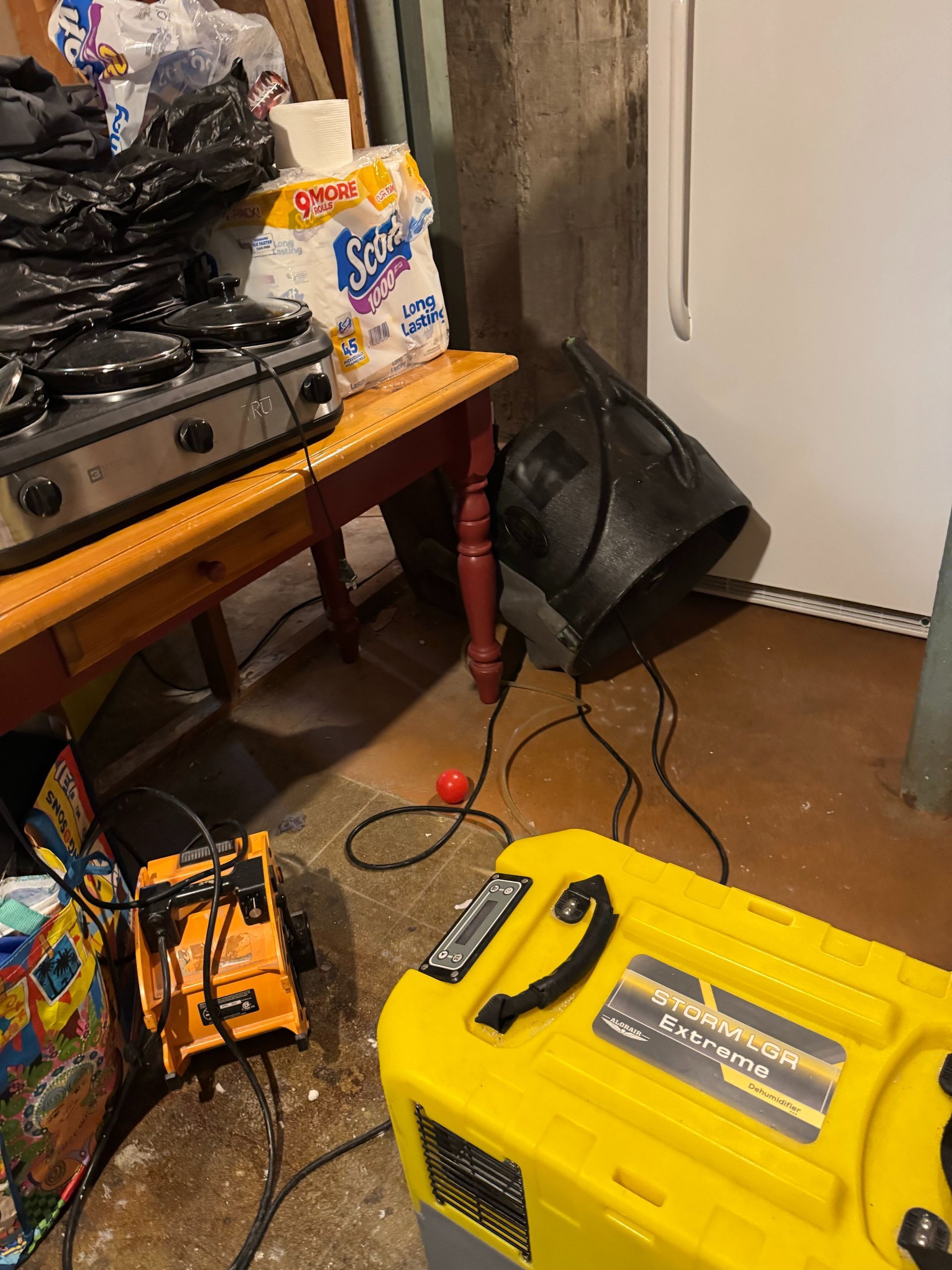 Cluttered room with a yellow portable generator, extension cords, a table, and stacked paper towels.