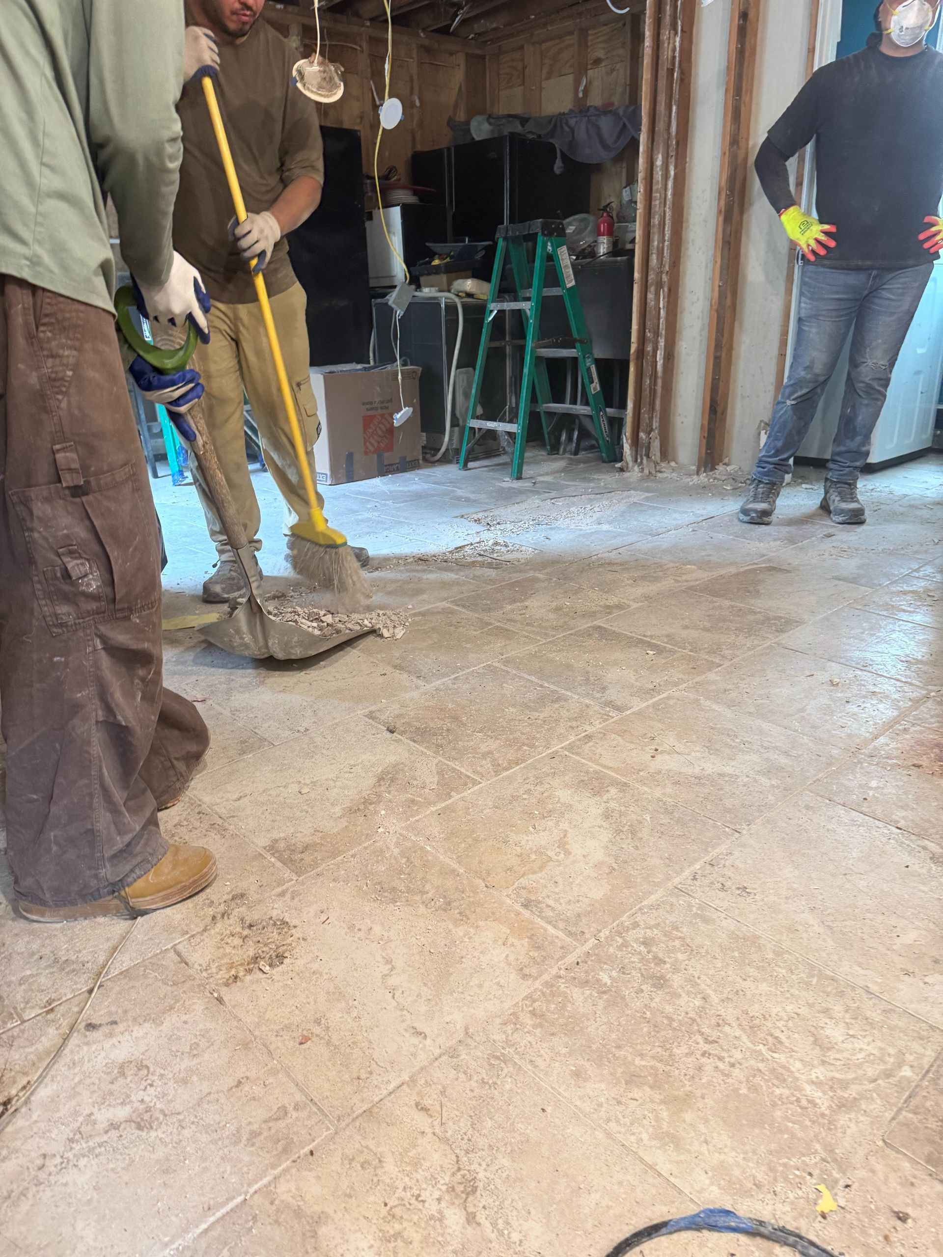 Workers cleaning debris in an unfinished room during renovation.