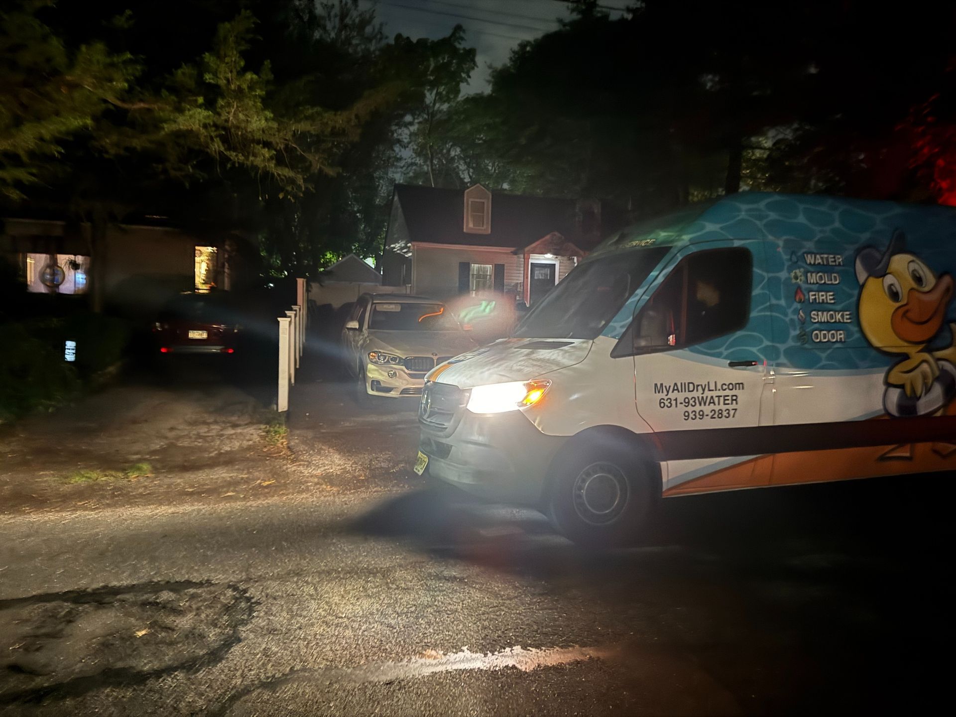 White delivery van with cartoon duck logo parked at night on a dark residential street