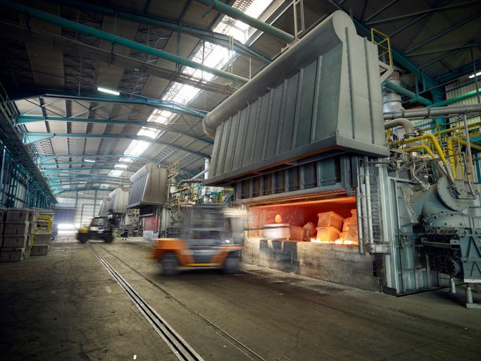 A forklift is driving in a factory next to a furnace.