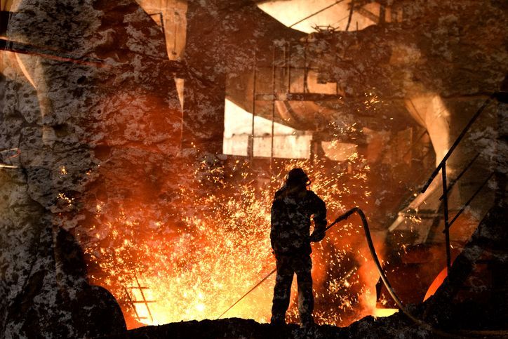 A man is standing in front of a large fire.