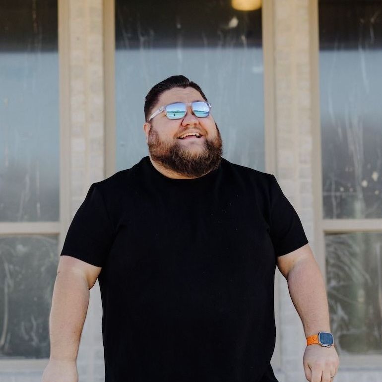 A man with a beard wearing sunglasses and a black shirt
