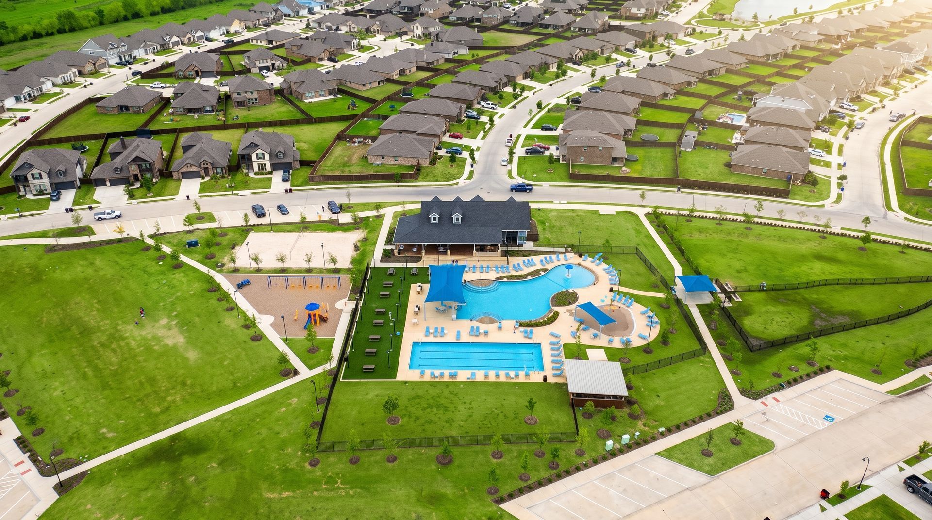 Aerial view of a suburban apartment complex with a central blue swimming pool and tennis courts