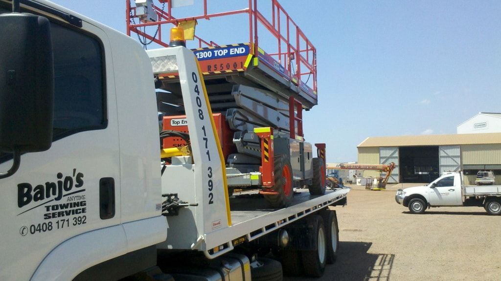 A flatbed tow truck with a scissor lift on its bed. Bright blue sky background. — Banjo's Anytime Towing in Humpty Doo, NT