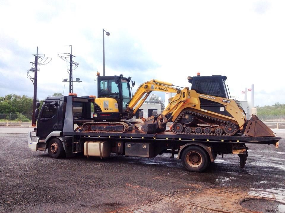 Truck Hauling a Yellow Excavator and Skid Steer on a Flatbed — Banjo's Anytime Towing in Darwin, NT