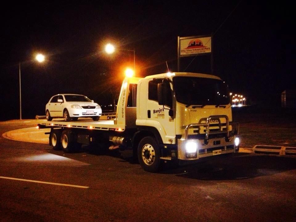 Tow truck with a white car on its flatbed at night — Banjo's Anytime Towing in Humpty Doo, NT