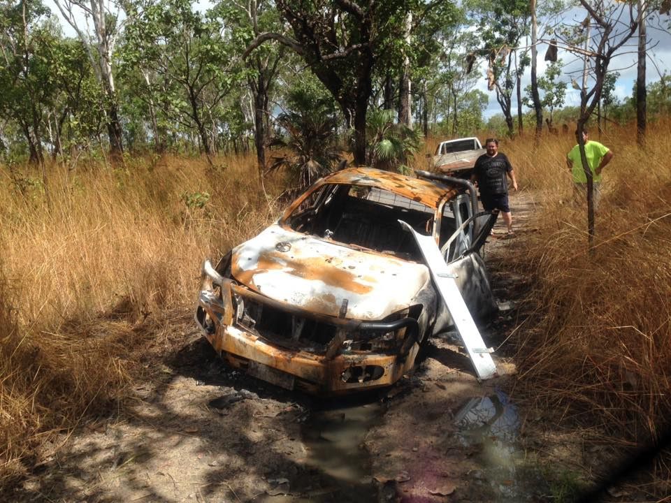 Burnt-out Suv on a Dirt Road; Two Men Standing Near Vehicle in Wooded Area — Banjo's Anytime Towing in Coolalinga, NT