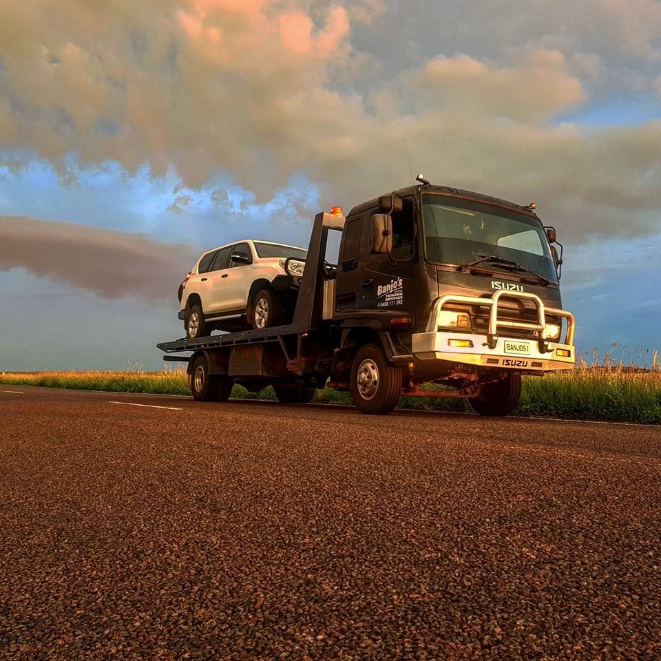 A Tow Truck Hauling a White Suv on a Rural Road at Sunset — Banjo's Anytime Towing in Humpty Doo, NT