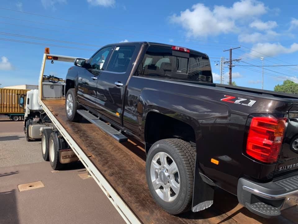 A dark brown pickup truck on a tow truck, against a blue sky — Banjo's Anytime Towing in Humpty Doo, NT