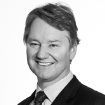 A man in a suit and tie is smiling in a black and white photo.