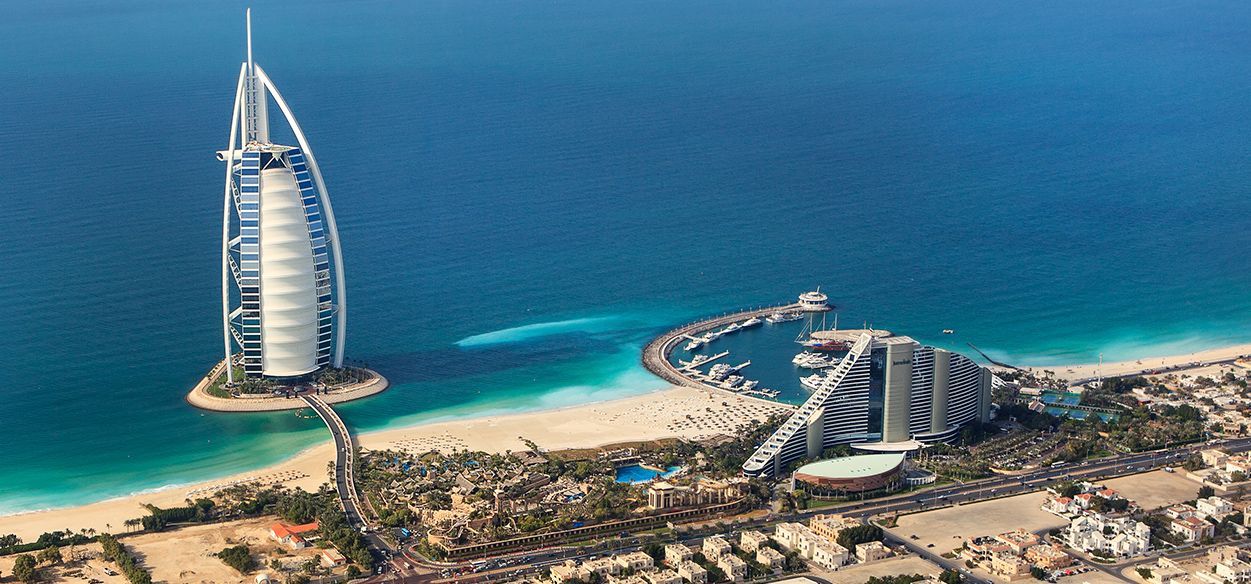An aerial view of a beach with a large building in the middle of the ocean.