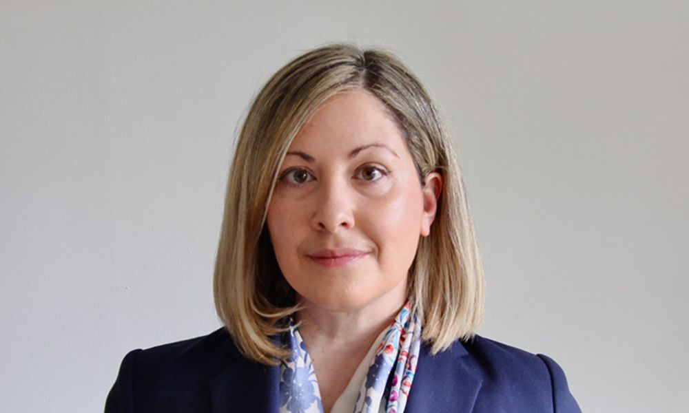 A woman in a blue jacket and scarf is smiling for the camera.