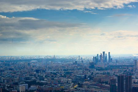 An aerial view of a city with a blue sky and clouds in the background.