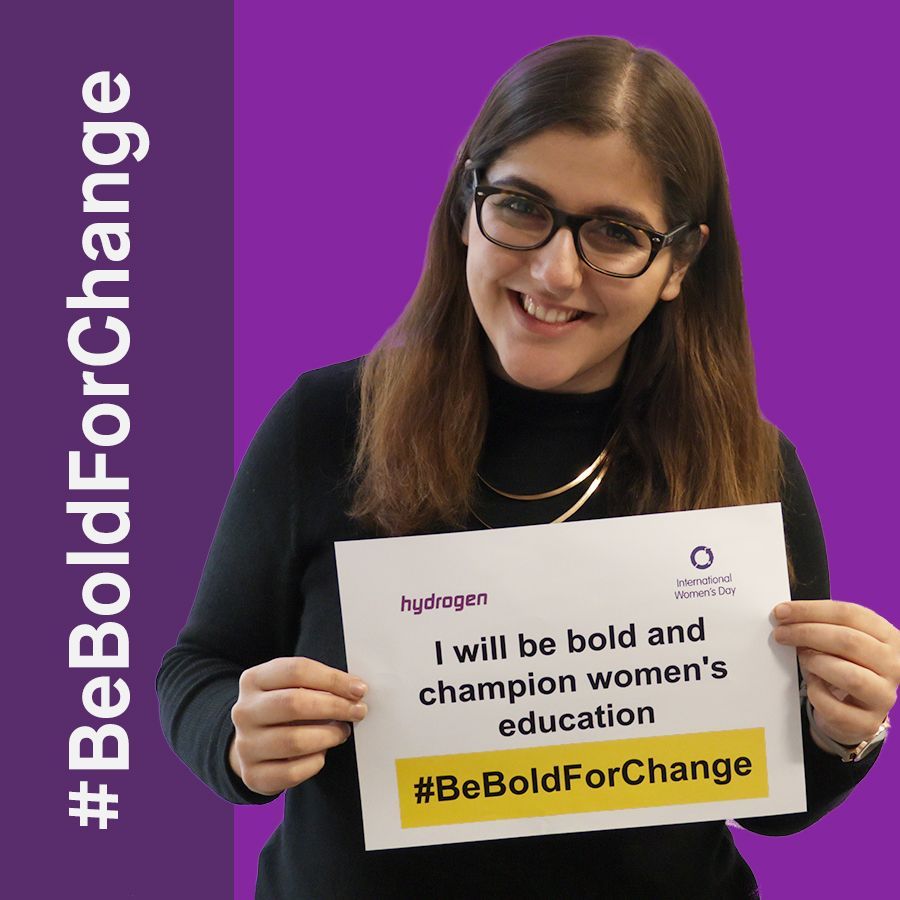 A woman is holding a sign that says i will be bold and champion women 's education.