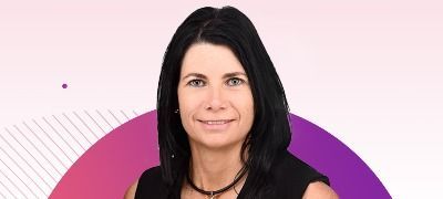 A woman with long black hair is smiling in front of a pink and purple circle.