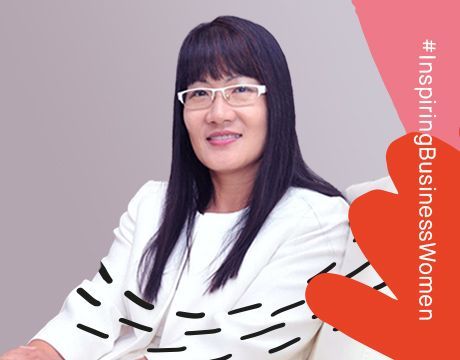 A woman wearing glasses and a white jacket is sitting in a chair.