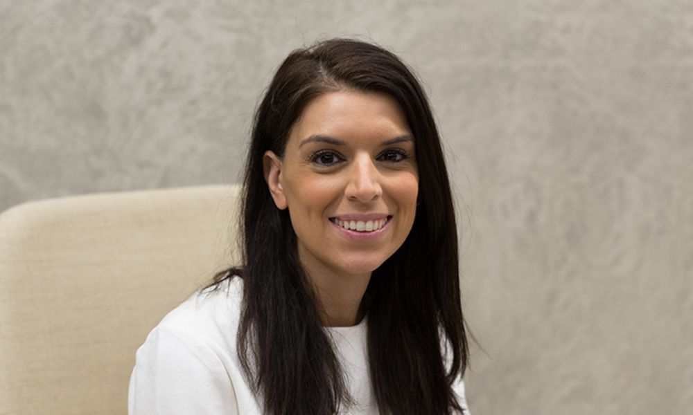A woman is sitting in a chair and smiling for the camera.