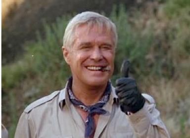 A man wearing a bandana and gloves is smiling and giving a thumbs up.