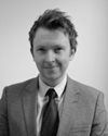 A man in a suit and tie is smiling in a black and white photo.