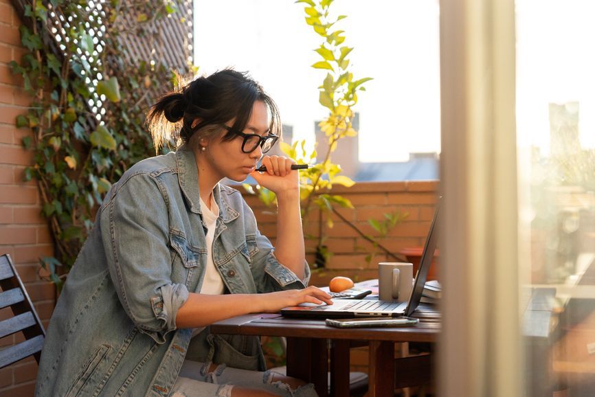 A woman is sitting at a table using a laptop computer.