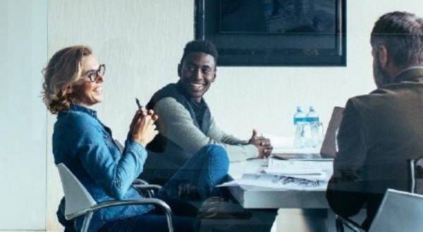 A group of people are sitting around a table in a conference room having a meeting.