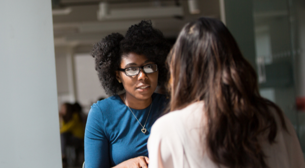 Two women are talking to each other in an office.