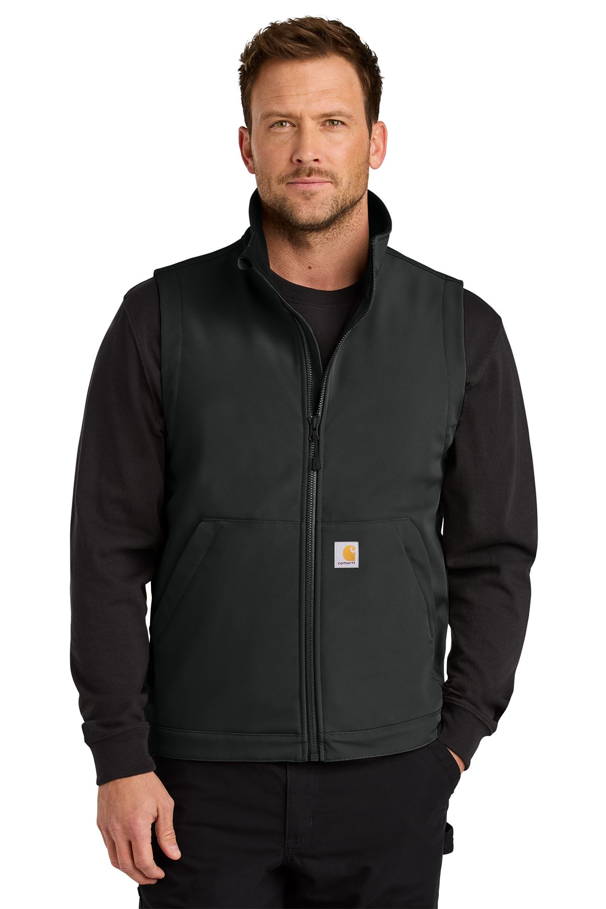 Man wearing a black Carhartt vest over a long-sleeved black shirt, standing.